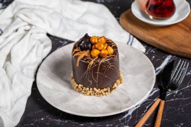 Koyu mermer masada karamel ve çikolatalı pasta. Tabakta lezzetli bir pasta