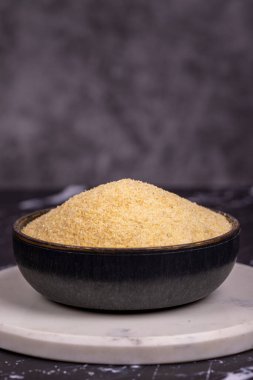 Koyu arkaplanda kurumuş organik irmik kokulu un. Kasede pişmemiş organik irmik. Kapat.