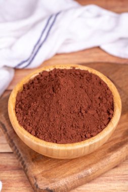 Ahşap arka planda kakao tozu. Tahta kasede kakao tozu