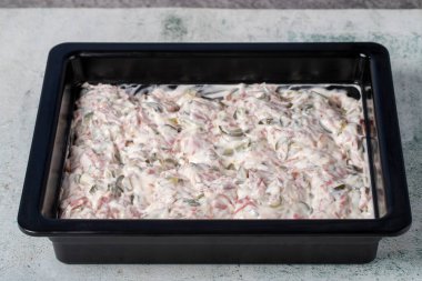 Gri arka planda İtalyan salatası. Bezelye, havuç, patates, salam, turşu ve mayonez ile hazırlanmış salata. sağlıklı çerezler