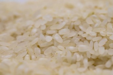 Arkaplan olarak çiğ pirinç yığını, arka plan olarak baklagiller. Pişmemiş kuru pirincin yakın çekimi.