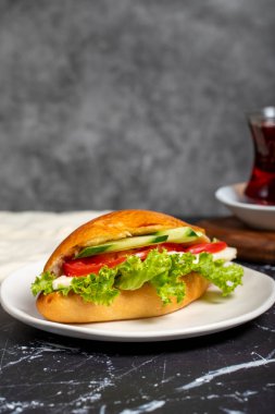 Peynirli sandviç, domates, salatalık ve marul. Koyu arkaplanda lezzetli bir sandviç.