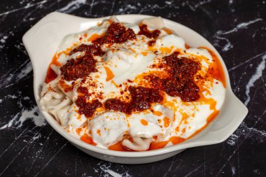 Soslu ve yoğurtlu Ravioli. Karanlık bir arka planda Ravioli. Türk mutfağı lezzetleri. Kapat.