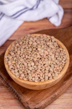 Ahşap arka planda yeşil mercimek. Tahta kasede çiğ yeşil mercimek. Kapat.