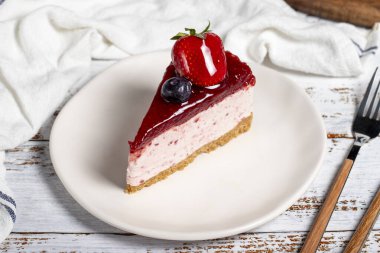 Meyveli kek dilimi. Ahşap arka planda böğürtlen soslu cheesecake dilimi