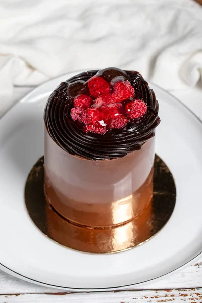 Chocolate cake. Raspberry, chocolate and cream cake on wood background
