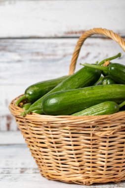 Hasır sepetteki taze salatalık ahşap arka planda. Salatalık hasat mevsimi konsepti. Sağlıklı bir diyet için sebzeler. Kapat.