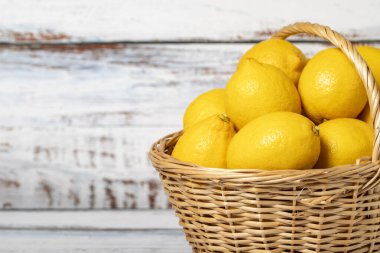 Tahta arka planda sepetin içinde taze limon. Limon hasat mevsimi. Sağlıklı bir diyet için sebzeler. Uzayı kopyala Metin için boş boşluk
