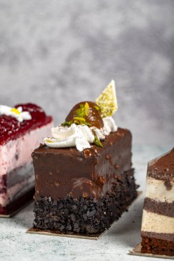 Bir sürü pasta dilimi. Tiramisu, çikolata ve arka planda meyveli kek. Kapat.