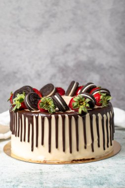 Çikolatalı pasta. Sıvı çikolata ve gri arka planda çilekli doğum günü pastası