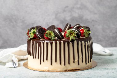 Çikolatalı pasta. Sıvı çikolata ve gri arka planda çilekli doğum günü pastası