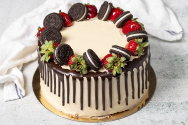 Çikolatalı pasta. Sıvı çikolata ve gri arka planda çilekli doğum günü pastası