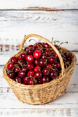 Tahta arka planda sepetin içinde taze kiraz. Kiraz hasadı mevsimi konsepti. Sağlıklı ve taze meyve. Kapat.