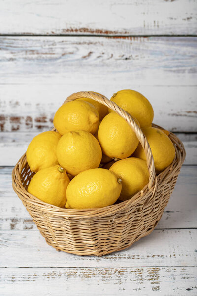 Fresh lemon in a wicker basket over wooden background. Lemon harvest season concept. Vegetables for a healthy diet. Close up
