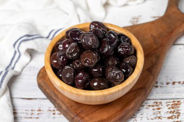 Tahta kasede siyah zeytin. Beyaz ahşap arka planda zeytinler. Akdeniz yemekleri. Vejetaryen yemeği. Kapat.