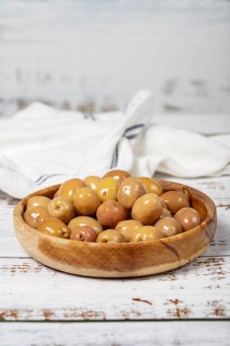 Ahşap kasede çizilmiş zeytin. Beyaz ahşap arka planda yeşil zeytin. Akdeniz yemekleri. vejetaryen yemeği