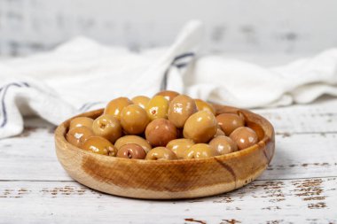 Ahşap kasede çizilmiş zeytin. Beyaz ahşap arka planda yeşil zeytin. Akdeniz yemekleri. vejetaryen yemeği