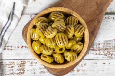 Ahşap kasede ızgara zeytin. Beyaz ahşap arka planda ızgara yeşil zeytin. Akdeniz yemekleri. Vejetaryen yemeği. Üst görünüm