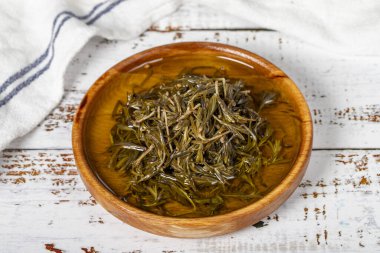 Tahta kasede zeytinyağlı siyah kekik. Beyaz ahşap arka planda Zahter. Akdeniz yemekleri. Vejetaryen yemeği. Kapat.