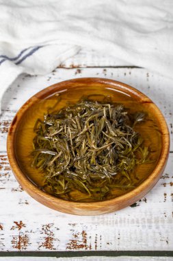 Tahta kasede zeytinyağlı siyah kekik. Beyaz ahşap arka planda Zahter. Akdeniz yemekleri. Vejetaryen yemeği. Kapat.