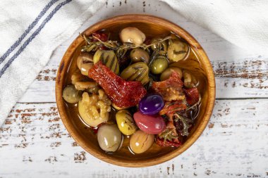 Tahta kasede zeytin salatası. Beyaz ahşap arka planda karışık zeytin. Akdeniz yemekleri. Vejetaryen yemeği. Üst görünüm