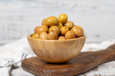 Büyük yeşil zeytin, ahşap kasede. Beyaz ahşap arka planda zeytinler. Akdeniz yemekleri. vejetaryen yemeği