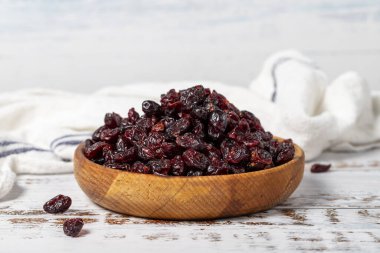 Ahşap kasede kuru yabanmersini. Beyaz ahşap arka planda güneşte kurutulmuş kuru kızılcık.