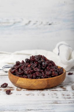 Ahşap kasede kuru yabanmersini. Beyaz ahşap arka planda güneşte kurutulmuş kızılcık. Kapat.