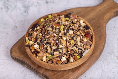 Kurutulmuş kış çayı. Tahta kasede güneşte kurutulmuş çay yaprakları. Kış çayı granüle elma, limon, portakal, zencefil, galangal, melissa, biberiye, karanfil, gül, ıhlamur, tarçın