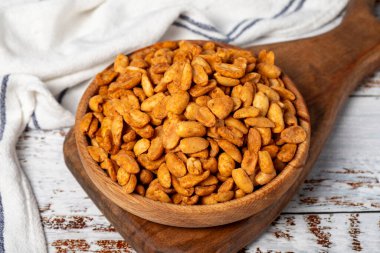 Ahşap kasede soslu fıstık. Beyaz ahşap arka planda soslu fıstıklar.