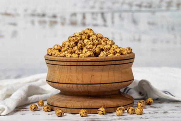 Roasted chickpeas in a wood bowl. Chickpeas on white wood background