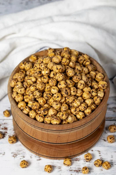 Roasted chickpeas in a wood bowl. Chickpeas on white wood background