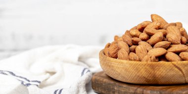 Tahta kasede badem. Beyaz ahşap arka planda kavrulmuş badem. Uzayı kopyala Metin için boş alan