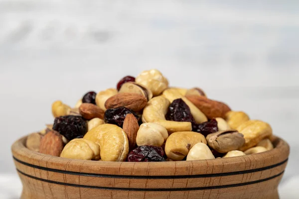 Mixed nuts in wood bowl. Nuts on white wood background. Mixed nuts prepared with hazelnuts, almonds, cashews, pistachios, pistachios and grapes. Close up