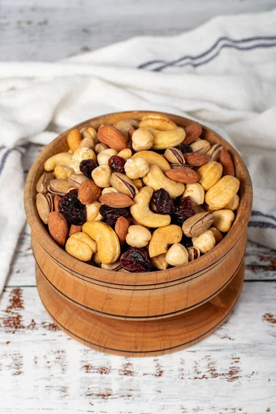 Mixed nuts in wood bowl. Nuts on white wood background. Mixed nuts prepared with hazelnuts, almonds, cashews, pistachios, pistachios and grapes