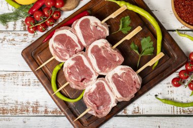 Ahşap arka planda kuzu fileto şişi. Çiğ kuzu fileto beyti şiş otlar ve baharatlarla. Üst görünüm