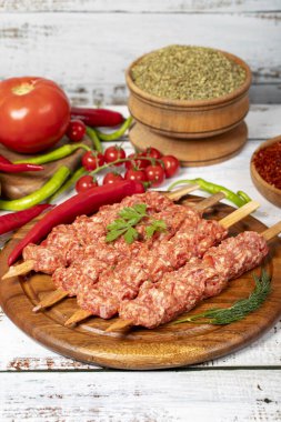 Ahşap arka planda Adana kebabı. Çiğ şiş adana kebabı, baharatlı ve otlu. Kapat.