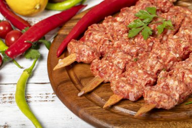 Ahşap arka planda Adana kebabı. Çiğ şiş adana kebabı, baharatlı ve otlu. Uzayı kopyala Metin için boş alan