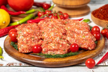 Ahşap arka planda köfteler. Çiğ et köftesi, baharatlı ve otlu.