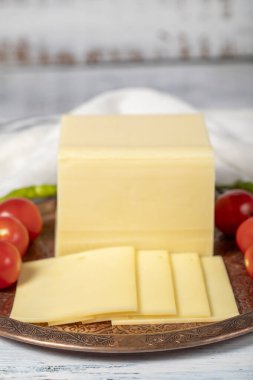 Bakır tabakta taze peynir ya da kaş kaval. Ahşap arka planda taze çedar peyniri. Yerel adı Kasar peyniri. Kapat.