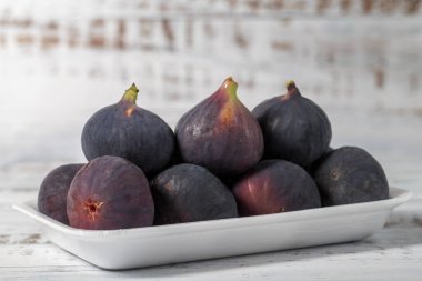 Beyaz ahşap arka planda taze incir paketlenmiş. Organik tarım ürünleri