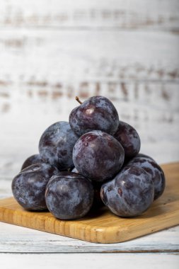 Beyaz ahşap arka planda taze siyah erikler. Organik tarım ürünleri. Lezzetli siyah erikler.