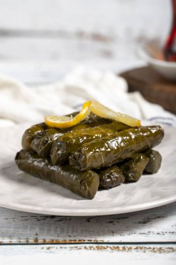 Zeytin yağıyla doldurulmuş üzüm yaprakları. Türk mutfağı lezzetleri. Beyaz arka planda lezzetli doldurulmuş üzüm yaprakları. Kapat.
