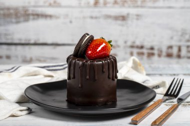 Çikolatalı pasta. Çilekli kek, bisküvi parçacıkları ve ahşap bir arka planda çikolata.