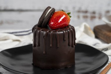 Çikolatalı pasta. Çilekli kek, bisküvi parçacıkları ve ahşap bir arka planda çikolata. Kapat.