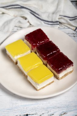 Küçük cheesecake kekleri. Beyaz arka planda küçük limonlu ve ahudududulu kek. Kapat.