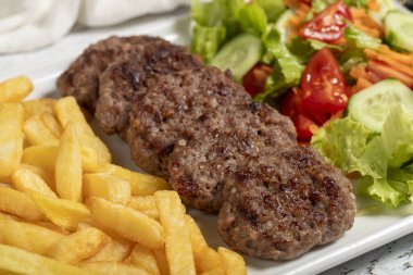Izgara köfte. Beyaz arka planda salata ve patates kızartması ile ızgara köfte. Kapat.