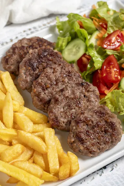 Grilled meat balls. Grilled meatballs with salad and fries on a white background. Close up