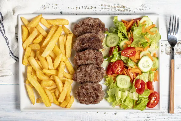 Grilled meat balls. Grilled meatballs with salad and fries on a white background