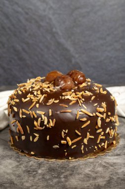 Çikolata, badem ve kestane keki. Karanlık arka planda doğum günü pastası. Kapat.